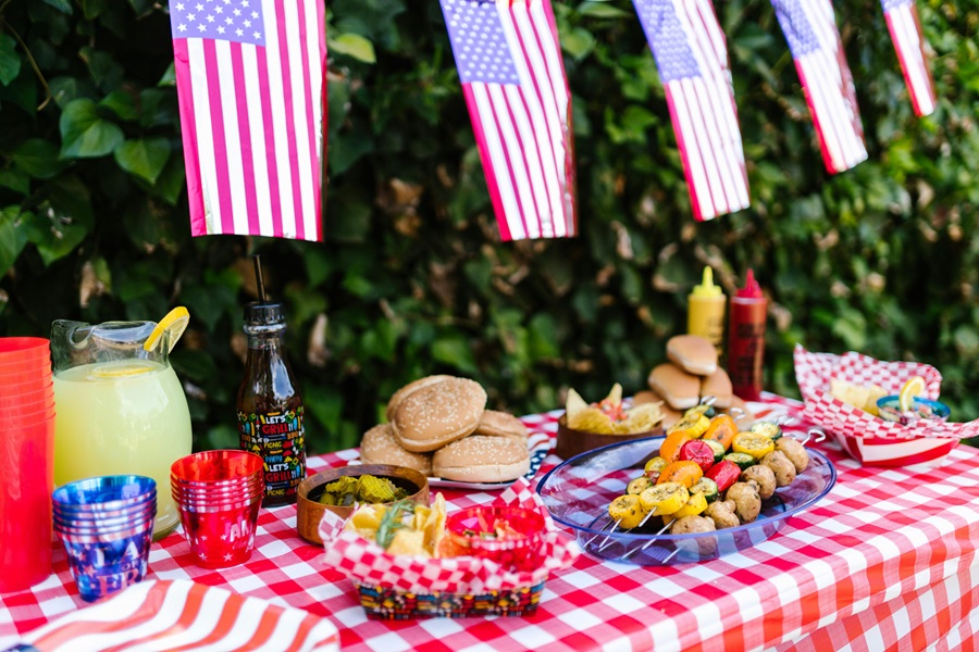 Easy Patriotic Food Appetizers for a Party a Picnic Table Filled with Food and an American Flag Bunting Above