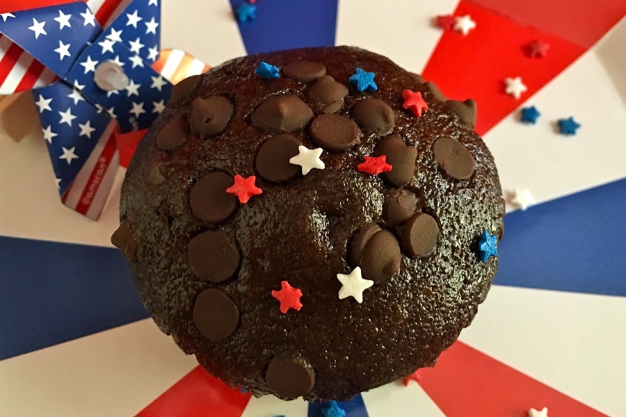 Memorial Day Pool Party Food Ideas Close Up of a Chocolate Muffin with Chocolate Chips and Red, White and Blue Star-Shaped Sprinkles on a Red, White and Blue Surface