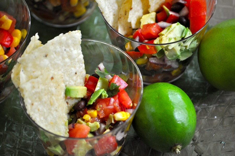 Memorial Day Pool Party Food Ideas Close Up of a Small Plastic Cup Filled with Salsa and Topped with Two Potato Chips