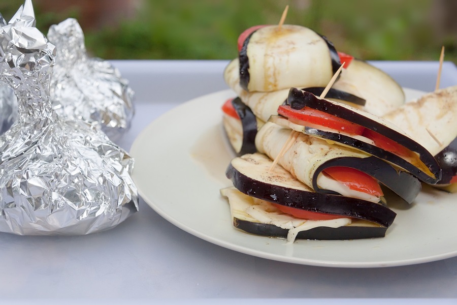 Summer Dinner Recipes for the Grill a Plate of Grilled Eggplant Next to Foil Packets on a Table Outside