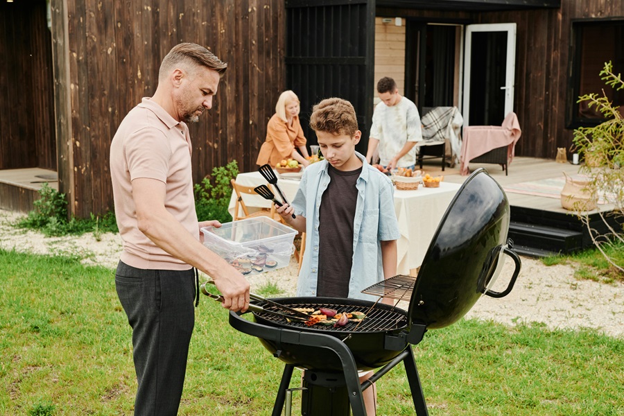 Summer Dinner Recipes for the Grill a Man and a Young Boy Standing by a Grill in a Backyard with People in the Background