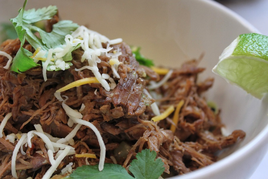 Easy Crockpot Beef Barbacoa Close Up of Barbacoa in a Bowl Topped with Shredded Cheese and Cilantro