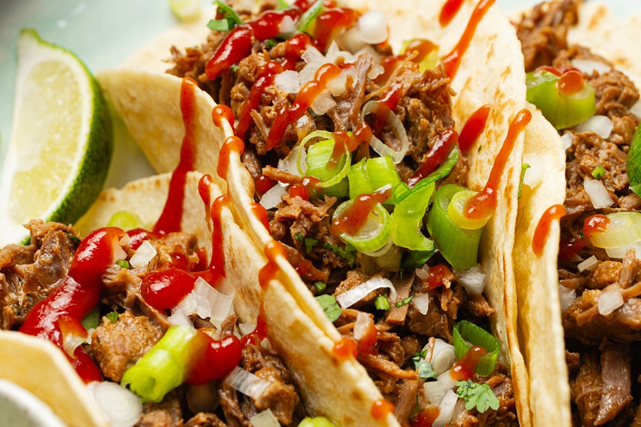 Close Up of Easy Crockpot Beef Barbacoa Tacos with Hot Sauce