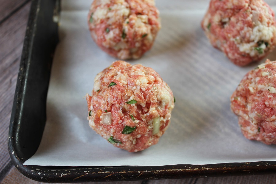 Easy Crockpot Meatballs Dinner Recipe Close Up of a Baking Sheet with Raw Meatballs on Parchment Paper