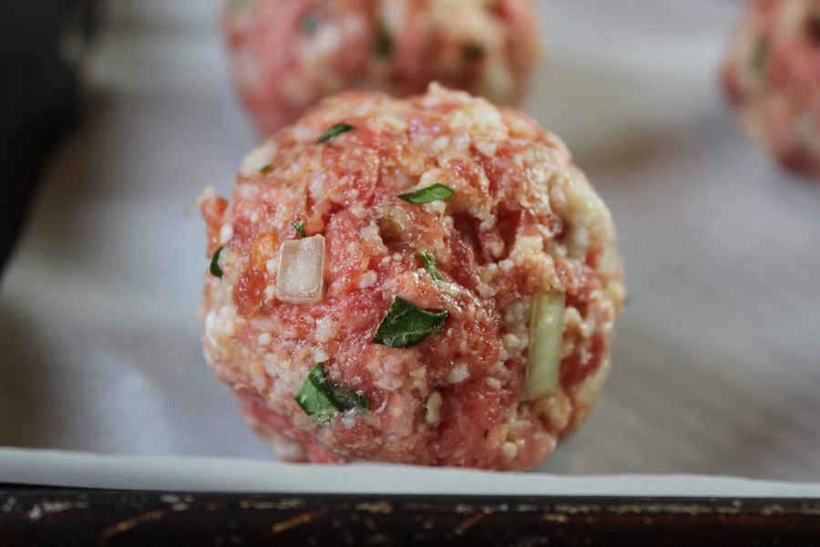 Easy Crockpot Meatballs Dinner Recipe Close Up of a Raw Meatball on Parchment Paper