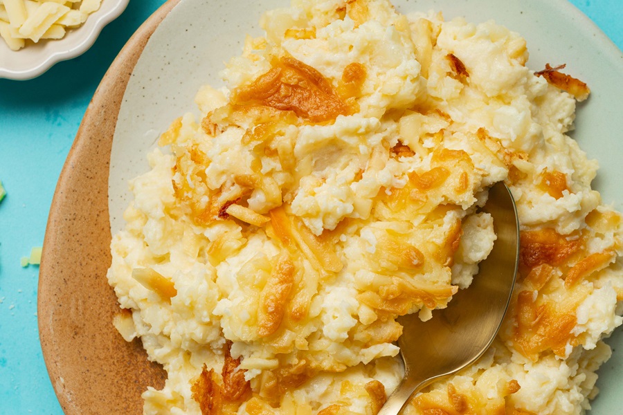 Easy Twice-Baked Mashed Potatoes Recipe Close Up of a Dish of Twice Baked Potatoes on a Blue Table