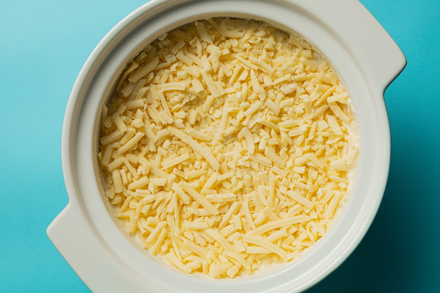 Easy Twice-Baked Mashed Potatoes Recipe Overhead View of a Baking Dish Filled with Mashed Potatoes and Topped with Shredded Cheese