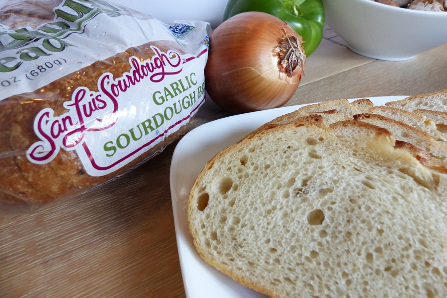 Pizza Sandwich Recipe Close Up of a White Plate with Sourdough Bread Slices Next to a Bag of Bread and an Onion