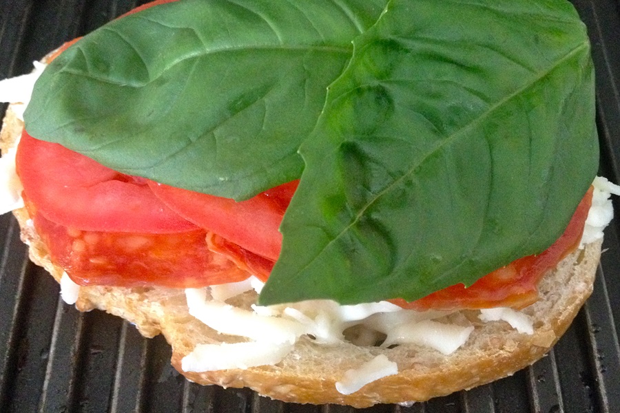 Pizza Sandwich Recipe Close Up of a Piece of Bread Topped with Cheese, Tomatoes, and Spinach on a Grill