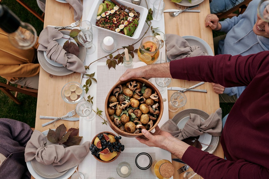 Southern Thanksgiving Recipes Overhead of a Table with People Passing Serving Platters Around with Thanksgiving Dishes