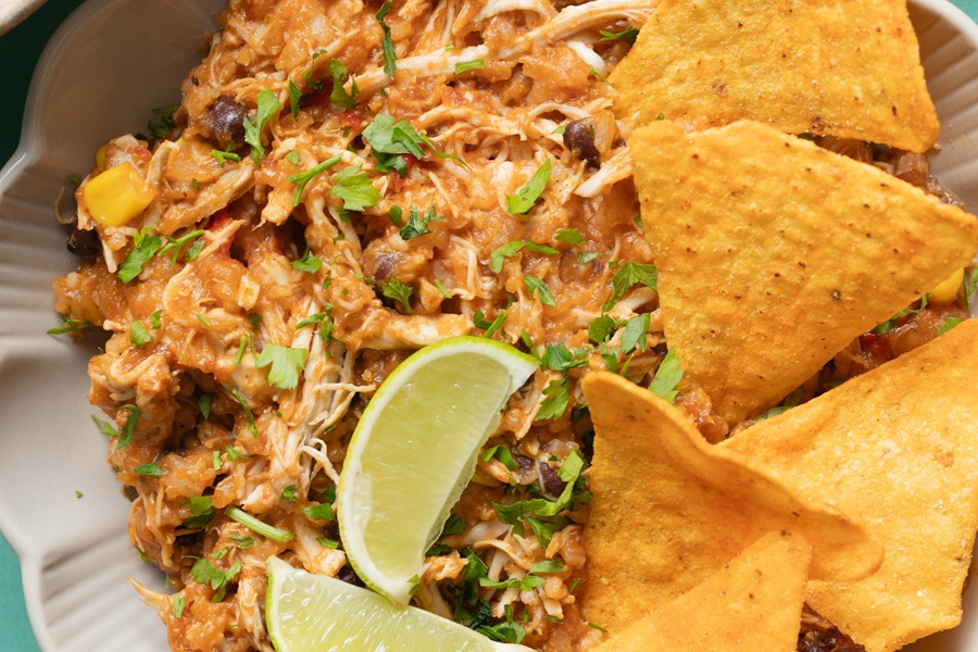 Easy Chicken Tacos in the Slow Cooker Recipe Extreme Close Up of Shredded Chicken with Lime Wedges and Tortilla Chips