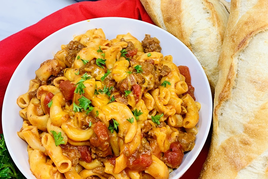 Easy Goulash in the Instant Pot a Plate of Goulash Next to Two Loaves of French Bread