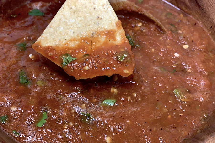 Salsa without Onions Recipe Close Up of a Chip Dipped in Salsa Over a Bowl of Salsa