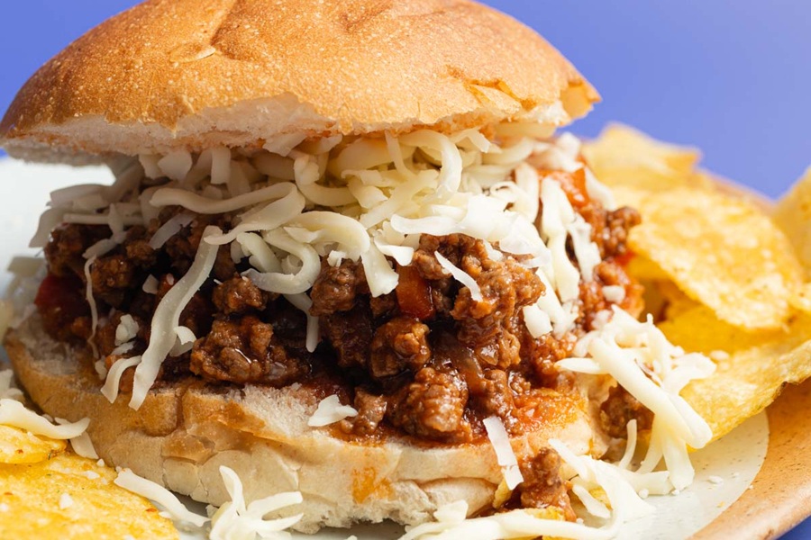 Crockpot Sloppy Joes Recipe a Sloppy Joe with Cheese on a Plate with Potato Chips