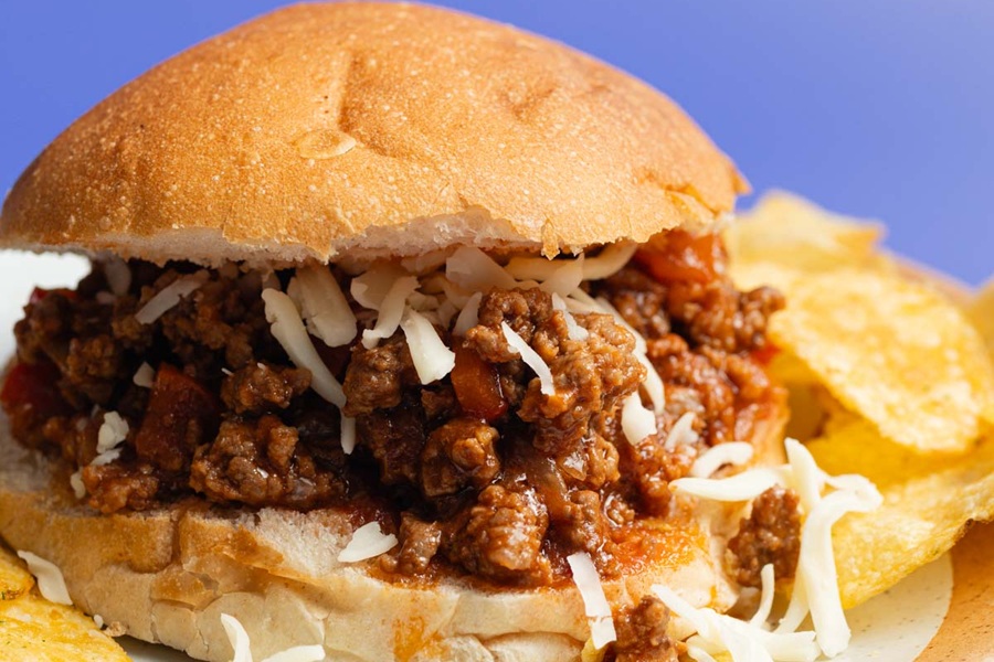 Crockpot Sloppy Joes Recipe Close Up of Cheese Topped Sloppy Joe with Potato Chips