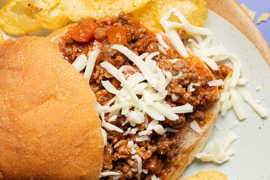 Crockpot Sloppy Joes Recipe a Sloppy Joe with the Top Bun Hanging Off the Meat Mixture Sprinkled with Cheese