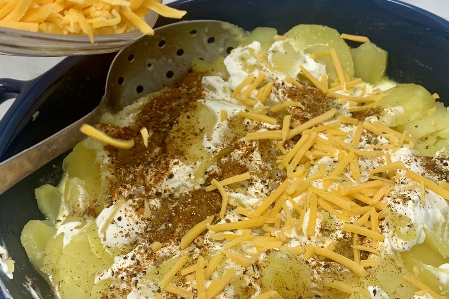 Easy Instant Scalloped Potatoes Close Up of Potatoes and Other Ingredients Inside an Instant Pot with a Metal Spoon