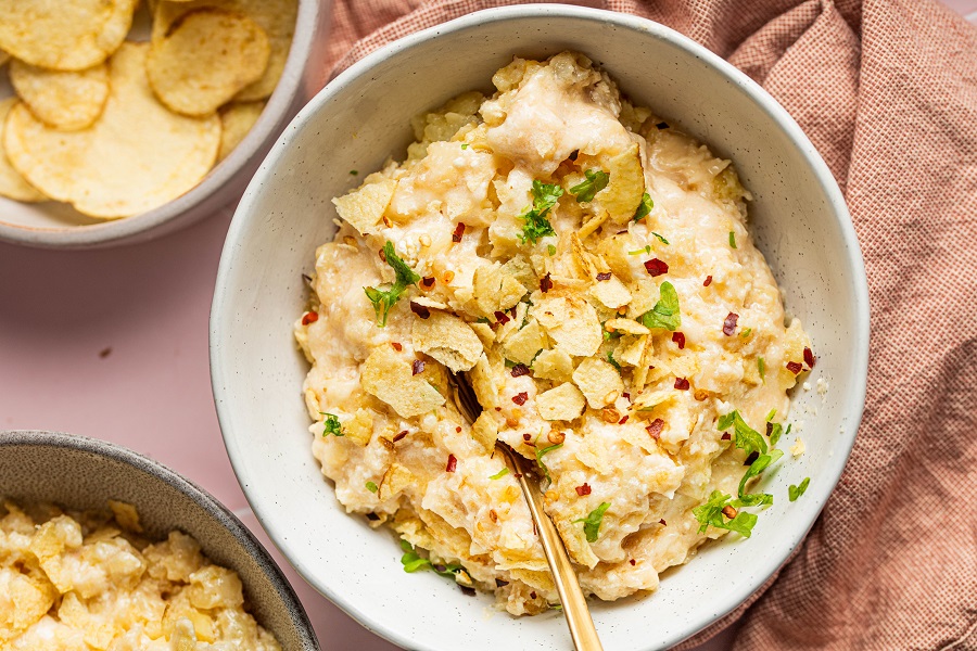 Cheesy Crockpot Hashbrown Potatoes Recipe Overhead View of a Bowl of Casserole with Parsley and Chips