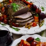 Crockpot Beef Pot Roast Recipe Cooked Roast on a Platter Sliced, and Surrounded by Roasted Veggies